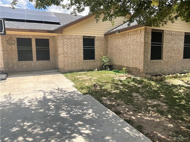3020 Nickel Ave, Mission, TX 78574 - view of exterior entry with solar panels, brick siding, and a shingled roof