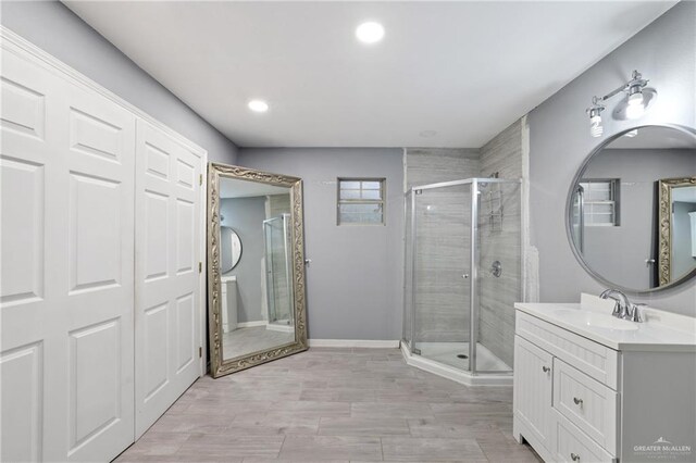 bathroom with baseboards, a stall shower, recessed lighting, and vanity