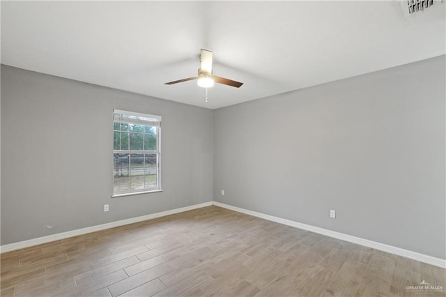 spare room featuring baseboards, visible vents, light wood-style floors, and a ceiling fan