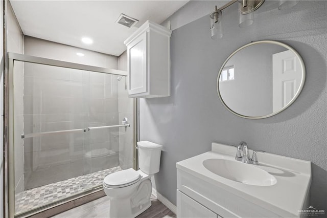full bath with vanity, toilet, baseboards, a stall shower, and visible vents