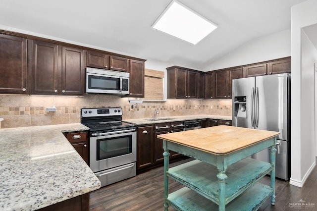 kitchen with appliances with stainless steel finishes, dark hardwood / wood-style floors, lofted ceiling, sink, and light stone counters