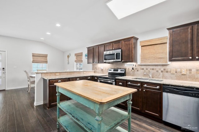 kitchen with stainless steel appliances, lofted ceiling with skylight, sink, and backsplash