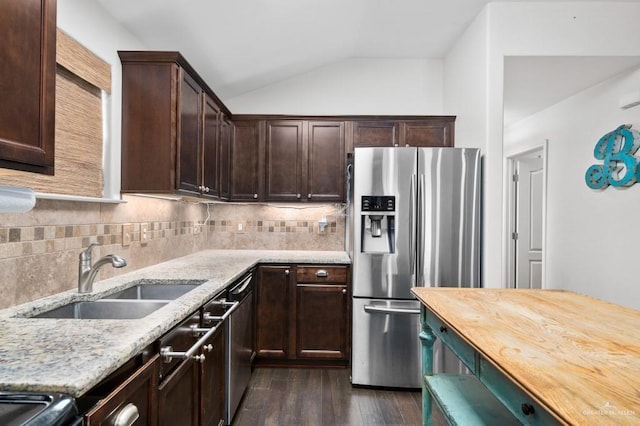 kitchen with sink, stainless steel appliances, light stone countertops, dark hardwood / wood-style flooring, and vaulted ceiling