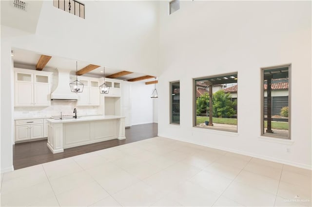 2502 Elbrus Ave, Edinburg, TX 78539 - kitchen with custom exhaust hood, beam ceiling, glass insert cabinets, light countertops, and tasteful backsplash
