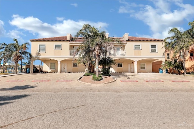102 E Gardenia St Unit 8, South Padre Island, TX 78597 - view of front of house featuring stucco siding, uncovered parking, and a tiled roof