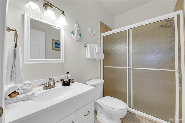 bathroom featuring vanity, toilet, and a shower with shower door