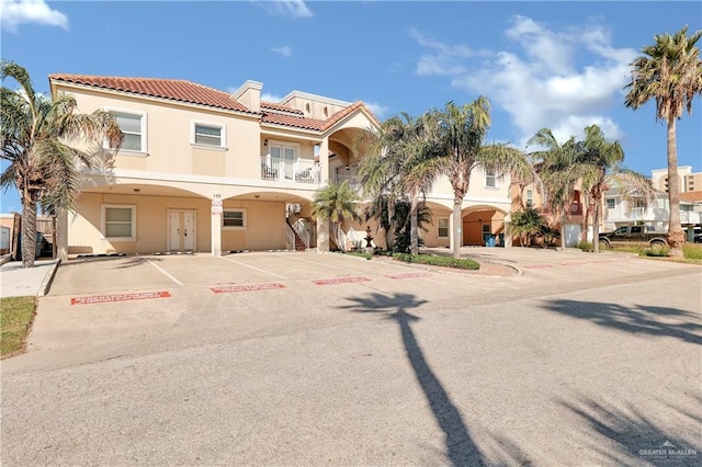 102 E Gardenia St Unit 8, South Padre Island, TX 78597 - view of front of property with stucco siding, a tiled roof, uncovered parking, french doors, and a balcony