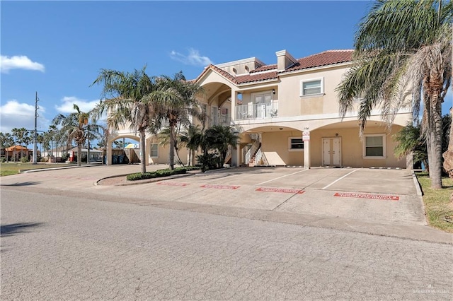 102 E Gardenia St Unit 8, South Padre Island, TX 78597 - mediterranean / spanish house with stucco siding, uncovered parking, a balcony, and a tile roof