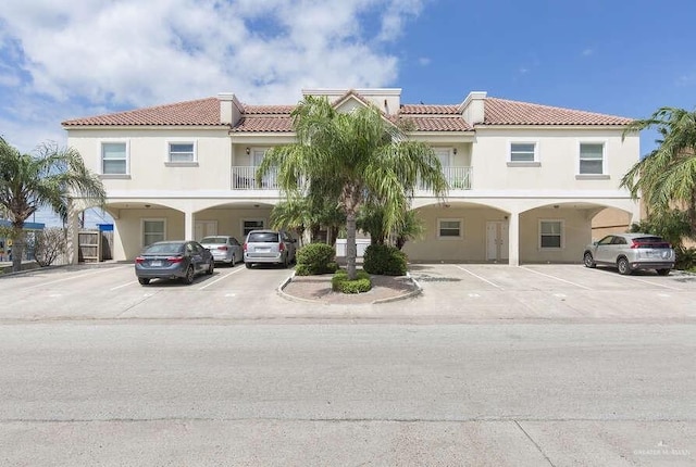102 E Gardenia St Unit 8, South Padre Island, TX 78597 - view of front of property featuring stucco siding, a tile roof, and uncovered parking
