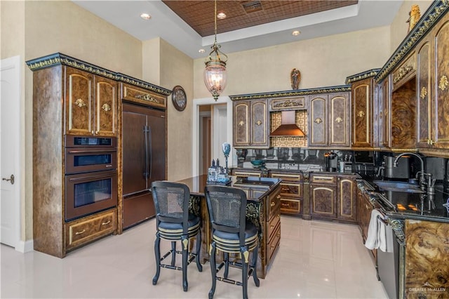 310A Padre Blvd Unit 3101, South Padre Island, TX 78597 - kitchen featuring built in refrigerator, wall chimney range hood, double oven, a kitchen island, and a tray ceiling