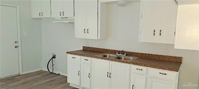 1217 S 1st St, Harlingen, TX 78550 - kitchen featuring dark countertops, light wood-type flooring, under cabinet range hood, and white cabinetry