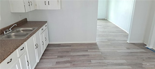 1217 S 1st St, Harlingen, TX 78550 - kitchen with white cabinetry, light wood-type flooring, and dark countertops