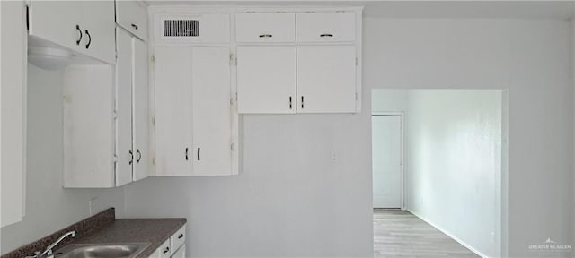 1217 S 1st St, Harlingen, TX 78550 - kitchen with white cabinetry, dark countertops, and light wood finished floors