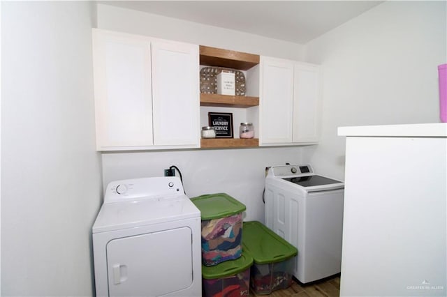 laundry room featuring cabinets, dark wood-type flooring, and washing machine and clothes dryer