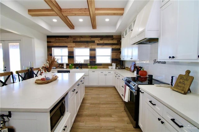 kitchen featuring a breakfast bar, white cabinets, a kitchen island, custom range hood, and stainless steel appliances