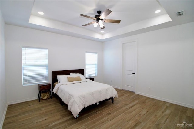 bedroom featuring a tray ceiling, ceiling fan, and wood-type flooring