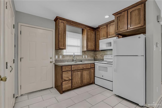 kitchen featuring backsplash, light tile patterned flooring, white appliances, and sink