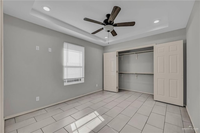 unfurnished bedroom featuring a closet, a tray ceiling, and ceiling fan