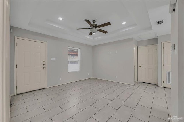 interior space featuring a raised ceiling, ceiling fan, and light tile patterned flooring