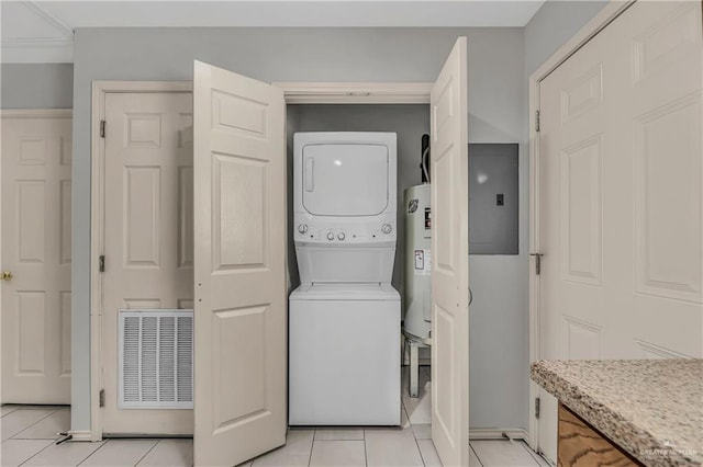 clothes washing area featuring light tile patterned flooring, electric panel, stacked washer and dryer, and water heater