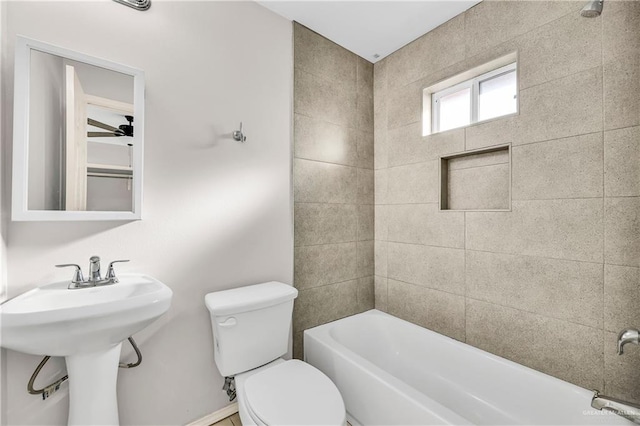 bathroom featuring tiled shower / bath combo and toilet