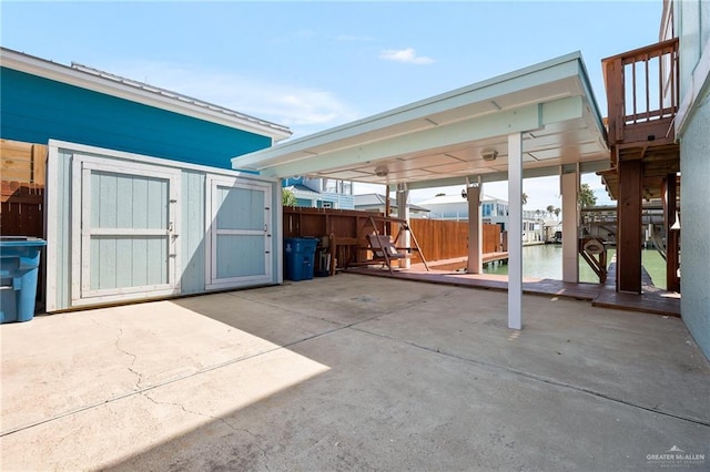 view of patio featuring a water view and a storage unit