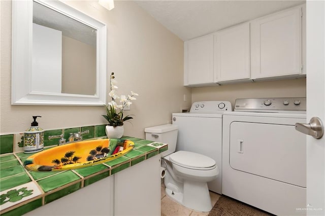 bathroom featuring washing machine and clothes dryer, tile patterned floors, sink, and toilet