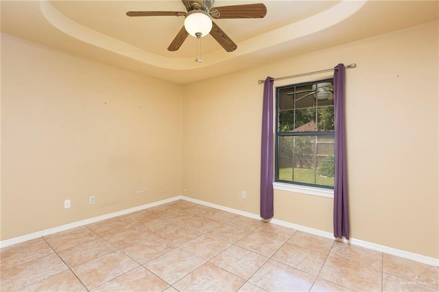 spare room featuring a raised ceiling, ceiling fan, and light tile patterned floors