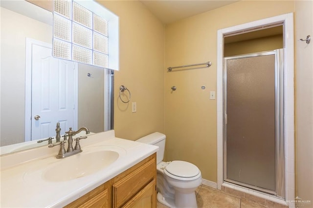 bathroom featuring tile patterned flooring, vanity, toilet, and a shower with door