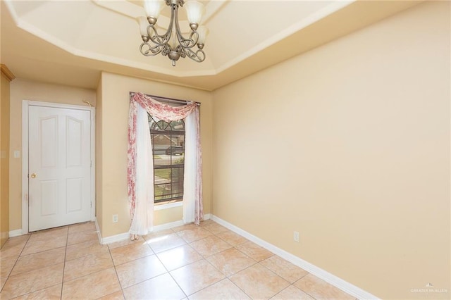 spare room featuring a raised ceiling, a notable chandelier, and light tile patterned flooring