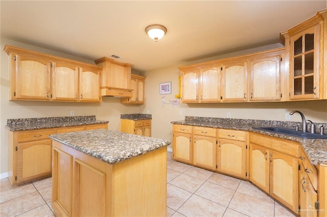 kitchen featuring light brown cabinetry, sink, a center island, and light tile patterned floors