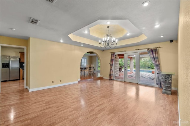3206 Marion Ct, Harlingen, TX 78550 - unfurnished room with arched walkways, a tray ceiling, a chandelier, light wood-type flooring, and recessed lighting