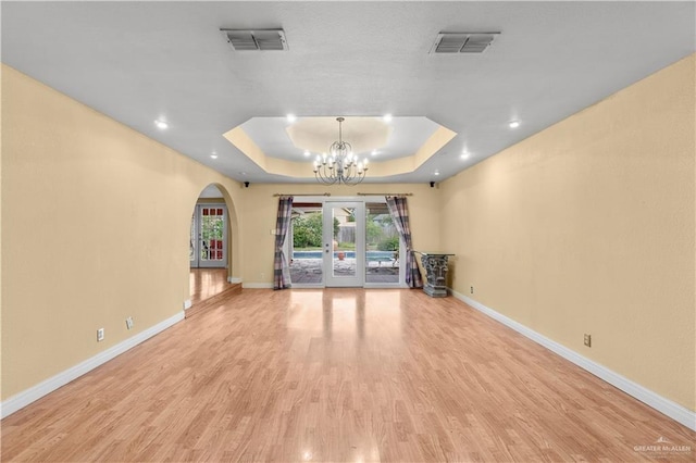 3206 Marion Ct, Harlingen, TX 78550 - unfurnished living room with arched walkways, a raised ceiling, a chandelier, light wood-style floors, and recessed lighting