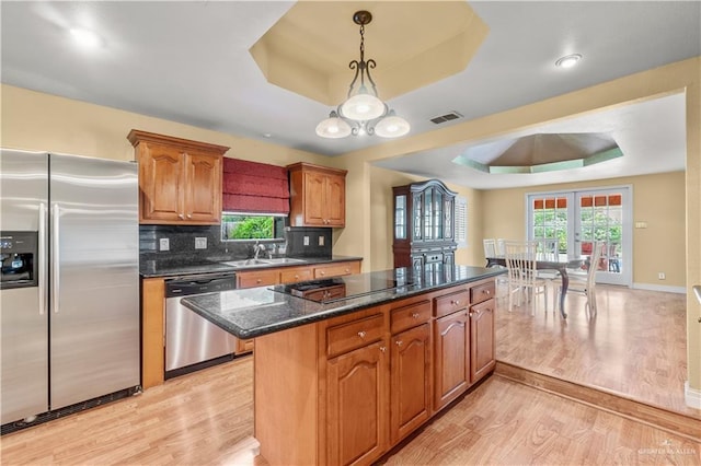 3206 Marion Ct, Harlingen, TX 78550 - kitchen featuring stainless steel appliances, a tray ceiling, light wood-style flooring, a center island, and decorative light fixtures