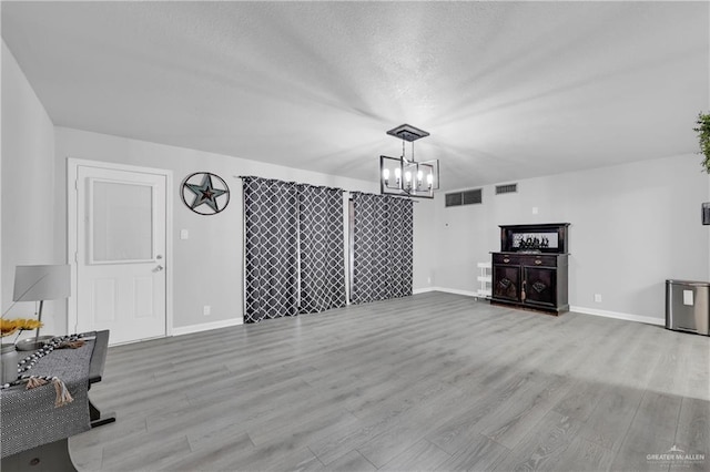 1702 Elmwood Dr, Harlingen, TX 78550 - unfurnished living room featuring a chandelier, wood finished floors, baseboards, and a textured ceiling