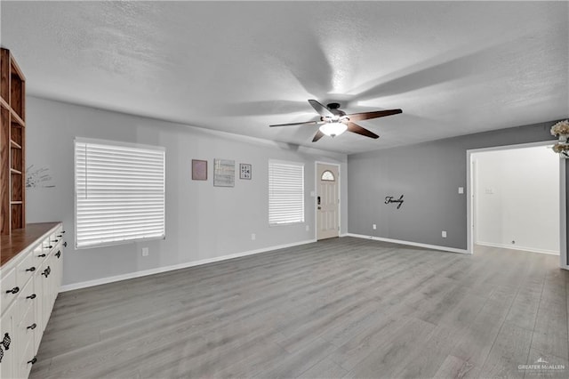 1702 Elmwood Dr, Harlingen, TX 78550 - unfurnished living room featuring ceiling fan, a textured ceiling, light wood-style floors, and baseboards