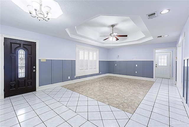 entrance foyer featuring ceiling fan with notable chandelier, a raised ceiling, and light tile patterned flooring