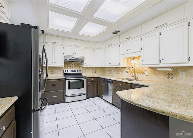 kitchen featuring sink, white cabinetry, light tile patterned floors, appliances with stainless steel finishes, and backsplash