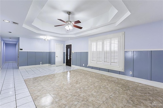 spare room with light tile patterned floors, a tray ceiling, and ceiling fan