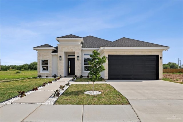 905 E 38th St E, San Juan, TX 78589 - prairie-style home featuring an attached garage, driveway, a front yard, stone siding, and roof with shingles