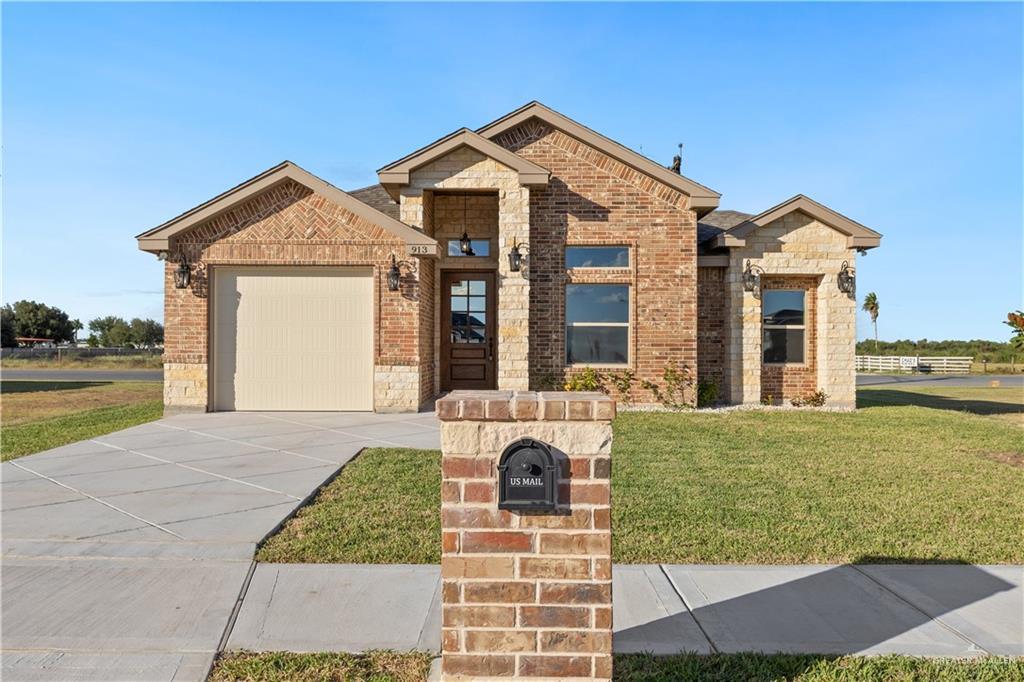 913 E Costa Del Sol Ave, Edinburg, TX 78542 - view of front of house featuring brick siding, a front lawn, an attached garage, and concrete driveway