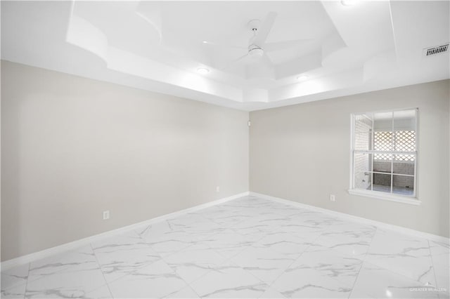 empty room featuring a raised ceiling and ceiling fan