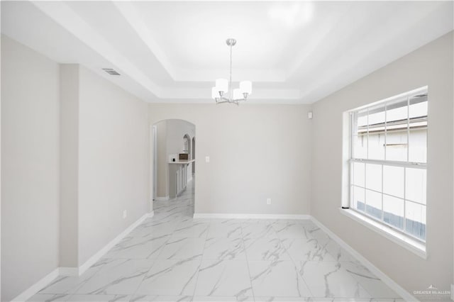 spare room with a notable chandelier and a raised ceiling