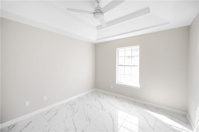 spare room featuring ceiling fan and a raised ceiling