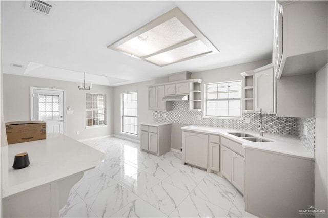 kitchen with sink, decorative backsplash, a wealth of natural light, and decorative light fixtures