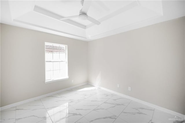 empty room with a raised ceiling and ceiling fan