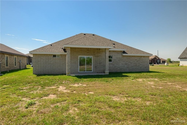 rear view of house with a patio area, a lawn, brick siding, and a shingled roof