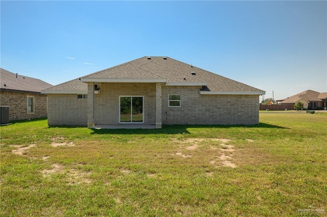 back of house with brick siding, a patio, a shingled roof, and a yard