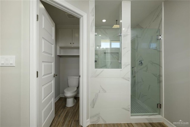 bathroom featuring toilet, wood finished floors, and a marble finish shower