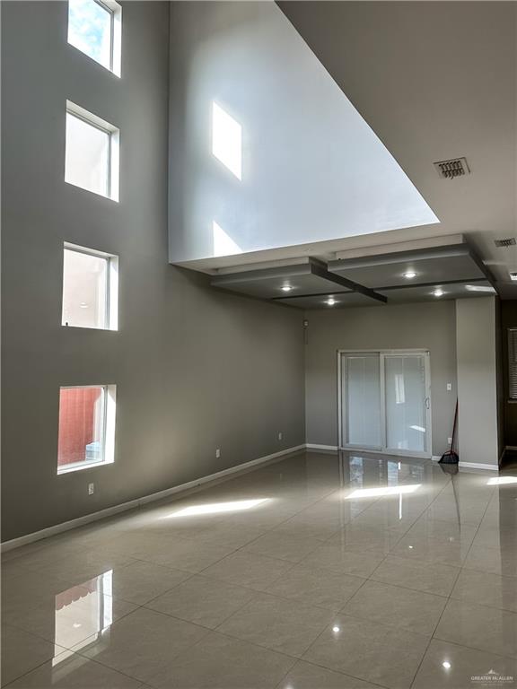 tiled empty room featuring a healthy amount of sunlight and a high ceiling